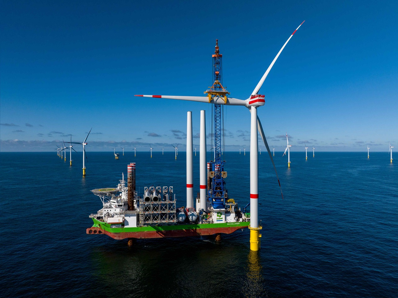 海に風力タービンを搭載した船、青い空と遠くの風力発電所。
