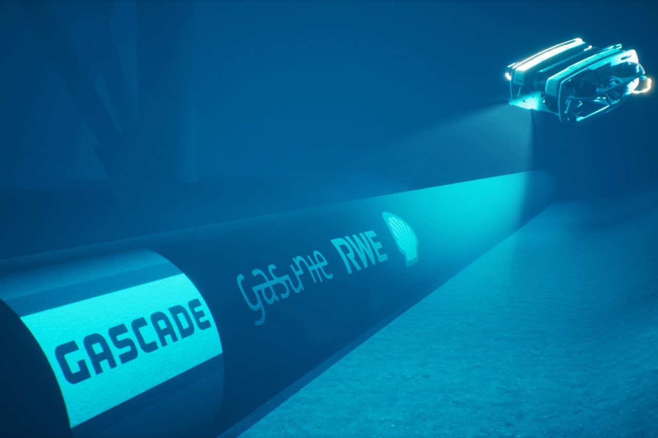Underwater view of a pipeline marked 'Gascade', illuminated by a small underwater vehicle.